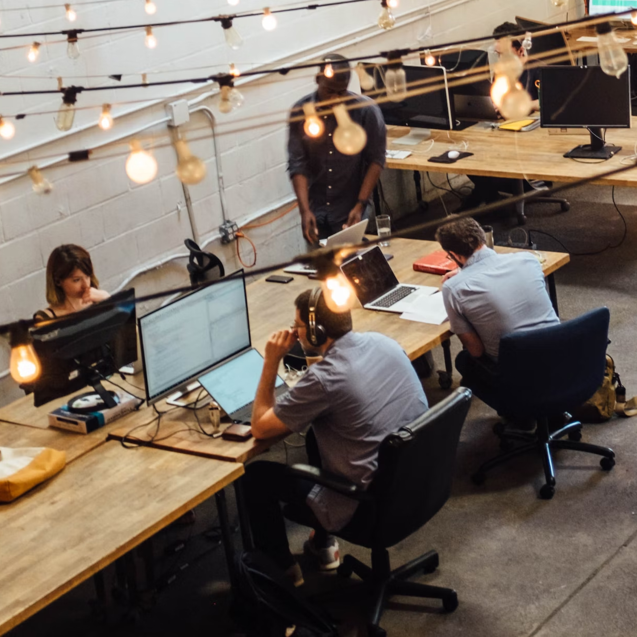 People are working at a communal table on laptops, which run Carbonite auto backup to protect against data loss.